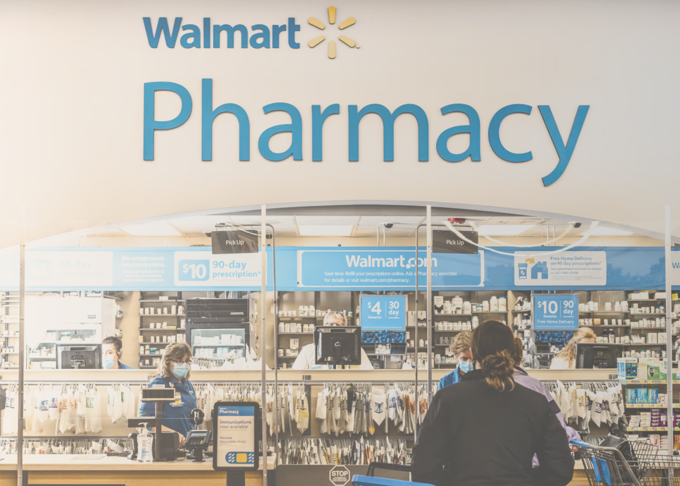 Walmart pharmacy technicians assisting customers inside a remodeled Supercenter